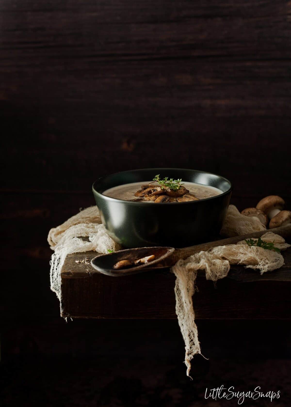 A bowl of creamy mushroom soup on a wooden board.