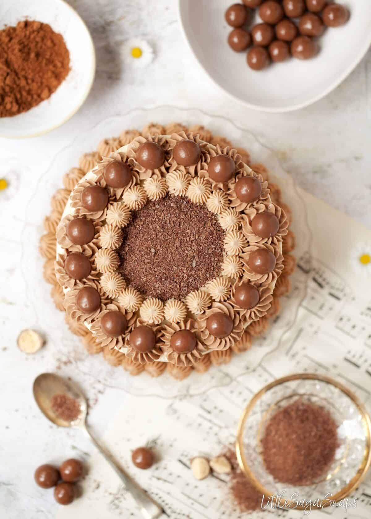 Flatlay view of a chocolate cake with italian meringue buttercream and malteser chocolate balls