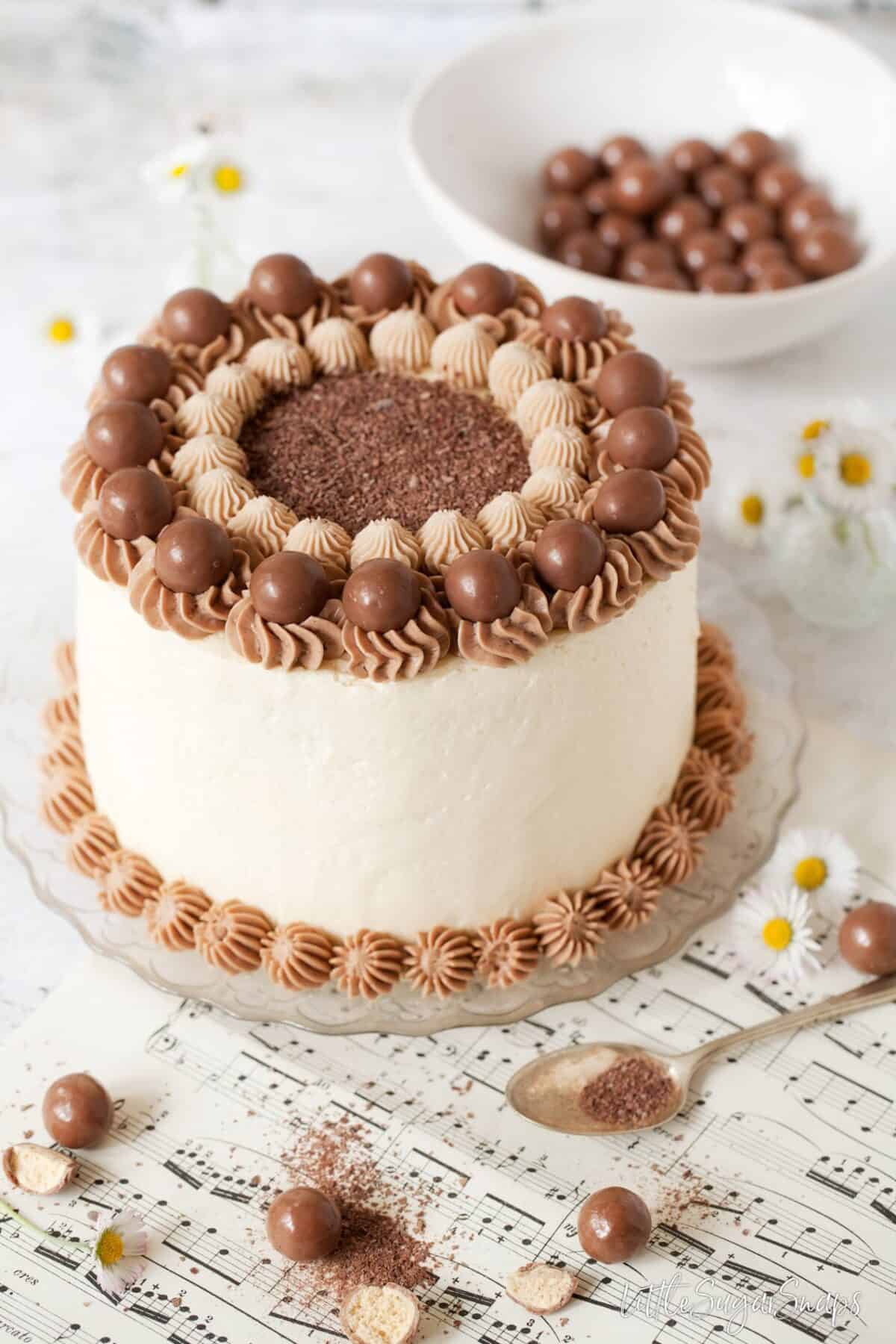 chocolate cake decorated with italian meringue buttercream and chocolate malt balls.