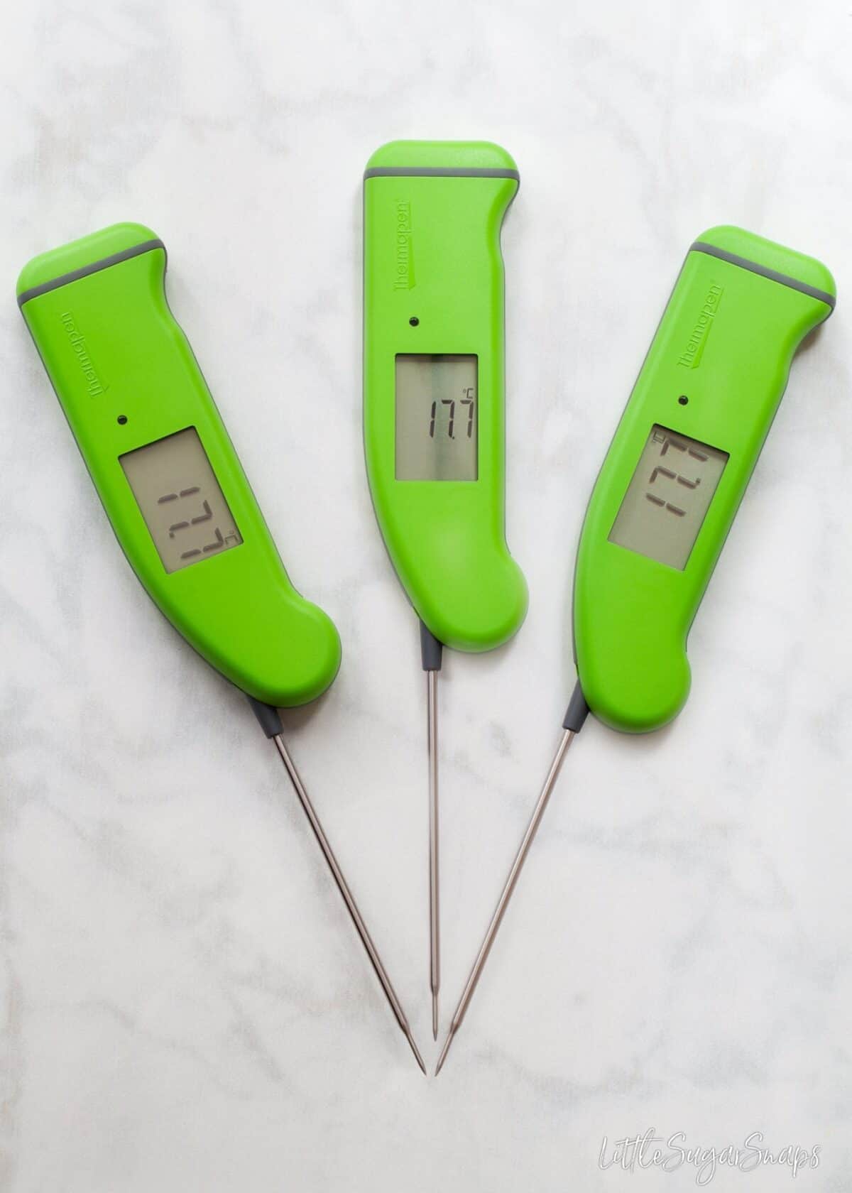 Three green food thermometers on a marble worktop