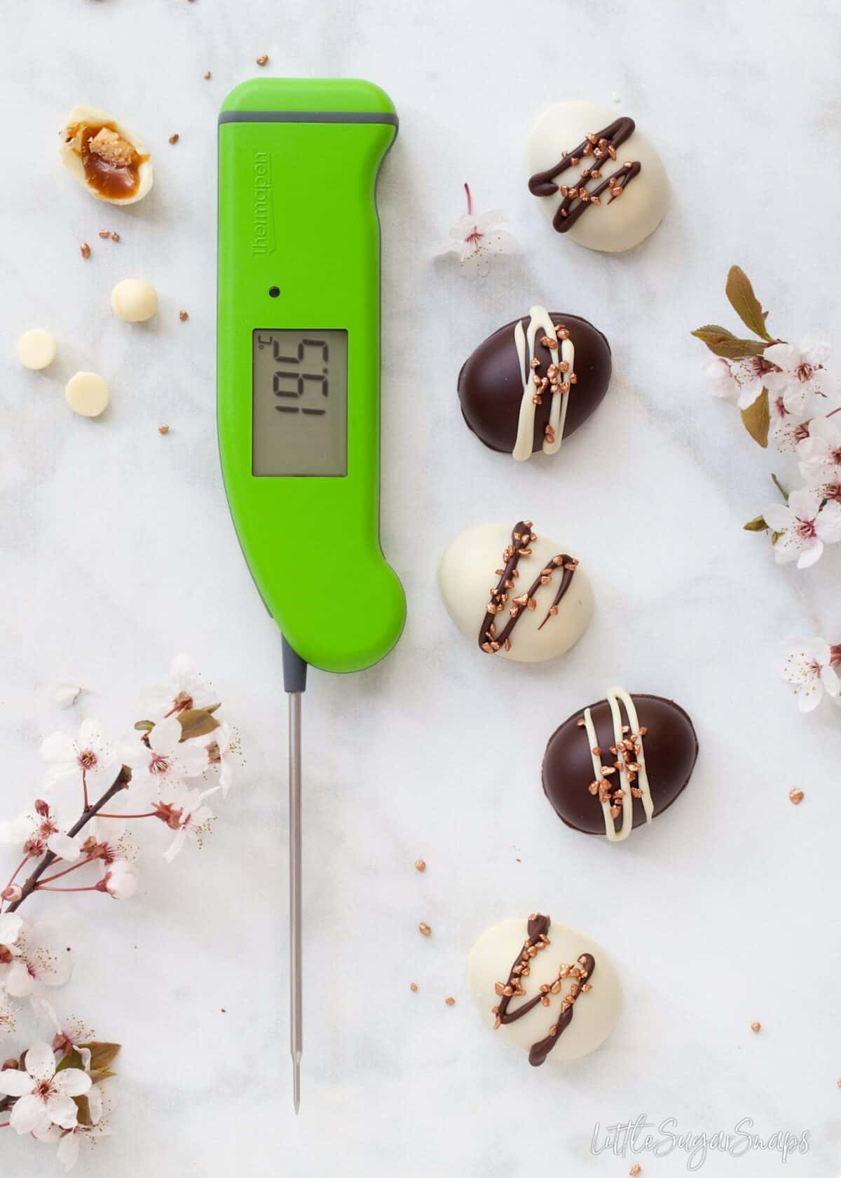 mini chocolate easter eggs and a bright green digital food thermometer on a marble worktop