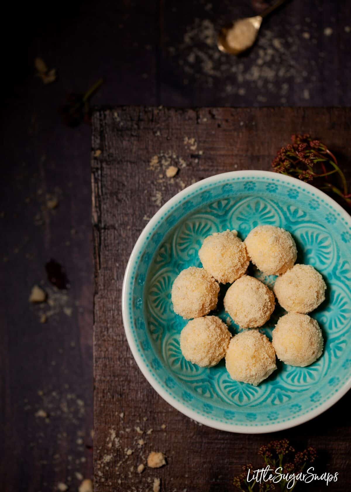 A blue bowl holding white chocolate truffles.