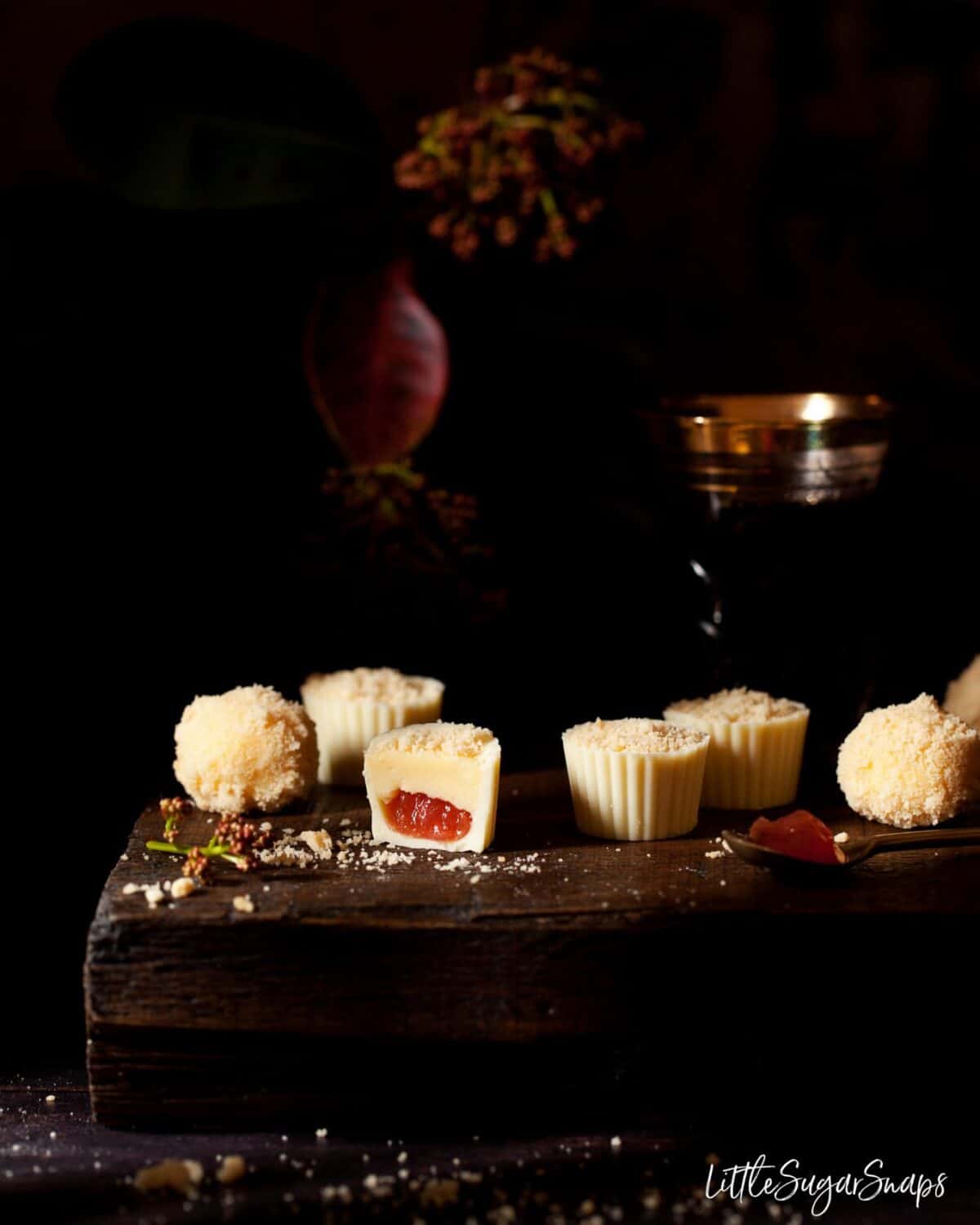 Various chocolates on a wooden table. One is cut open.