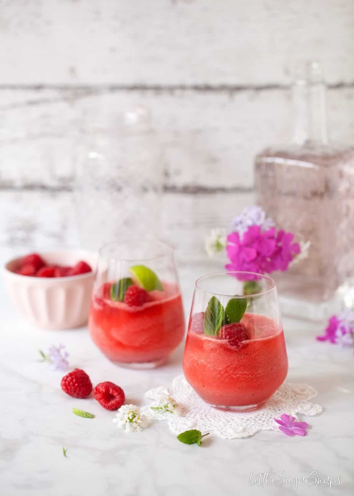 Two glasses of raspberry and mint frozen gin & tonic with flowers and pink gin