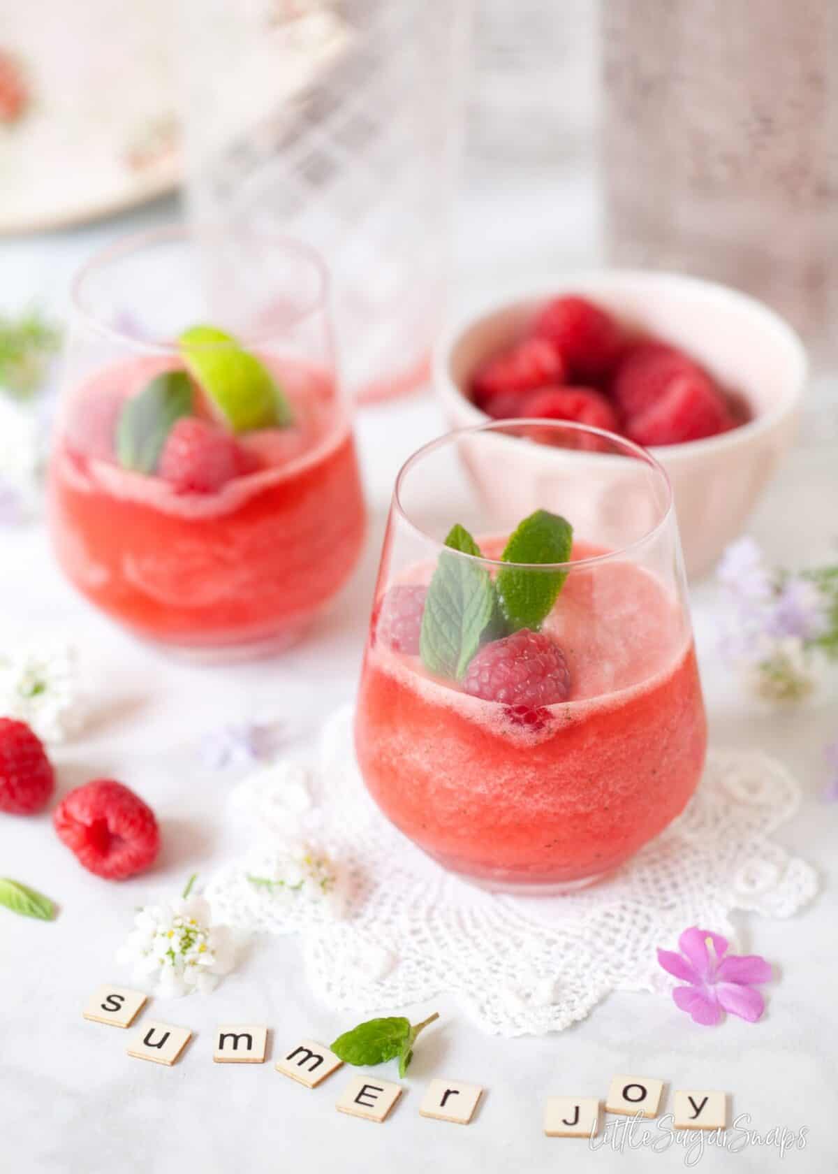 Frozen gin & tonic with raspberries and mint and 'summer joy' spelled out in letter tiles.