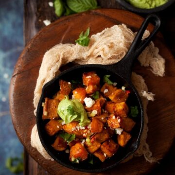 Chilli and feta sprinkled sweet potato cubes in small skillets with avocado feta dip