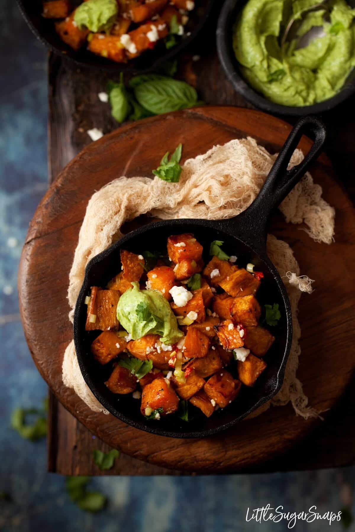 Chilli and feta sprinkled sweet potato cubes in small skillets with avocado feta dip 