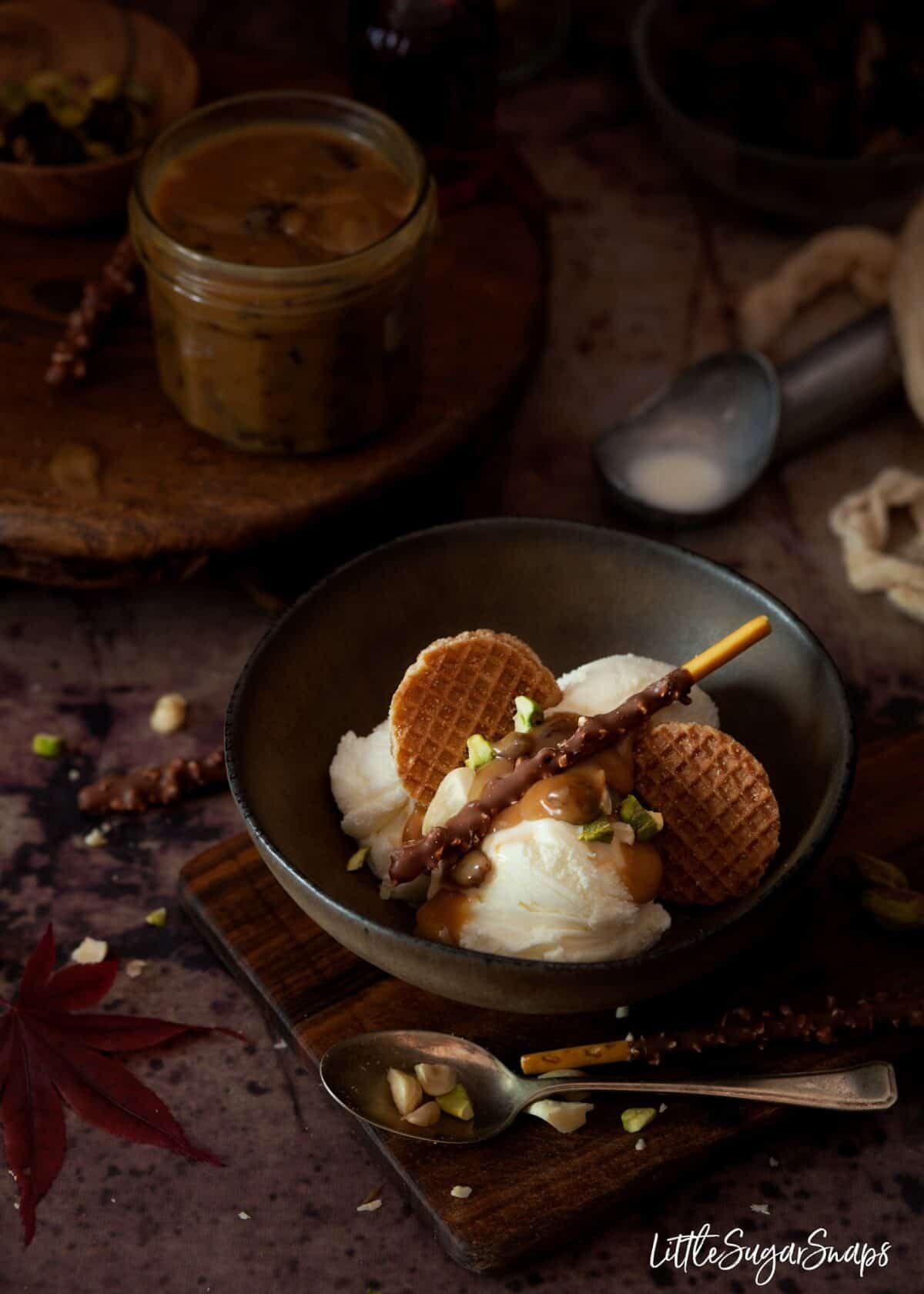 Caramel sauce in a bowl with vanilla ice cream, stroopwaffle and poke sticks