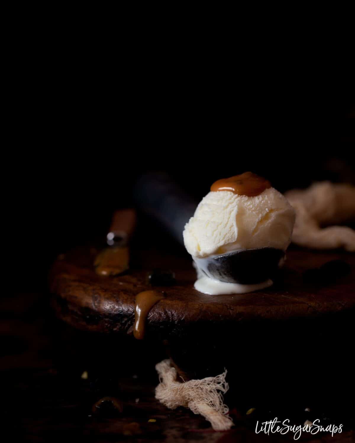 A scoop of vanilla ice cream with rum & raisin caramel sauce