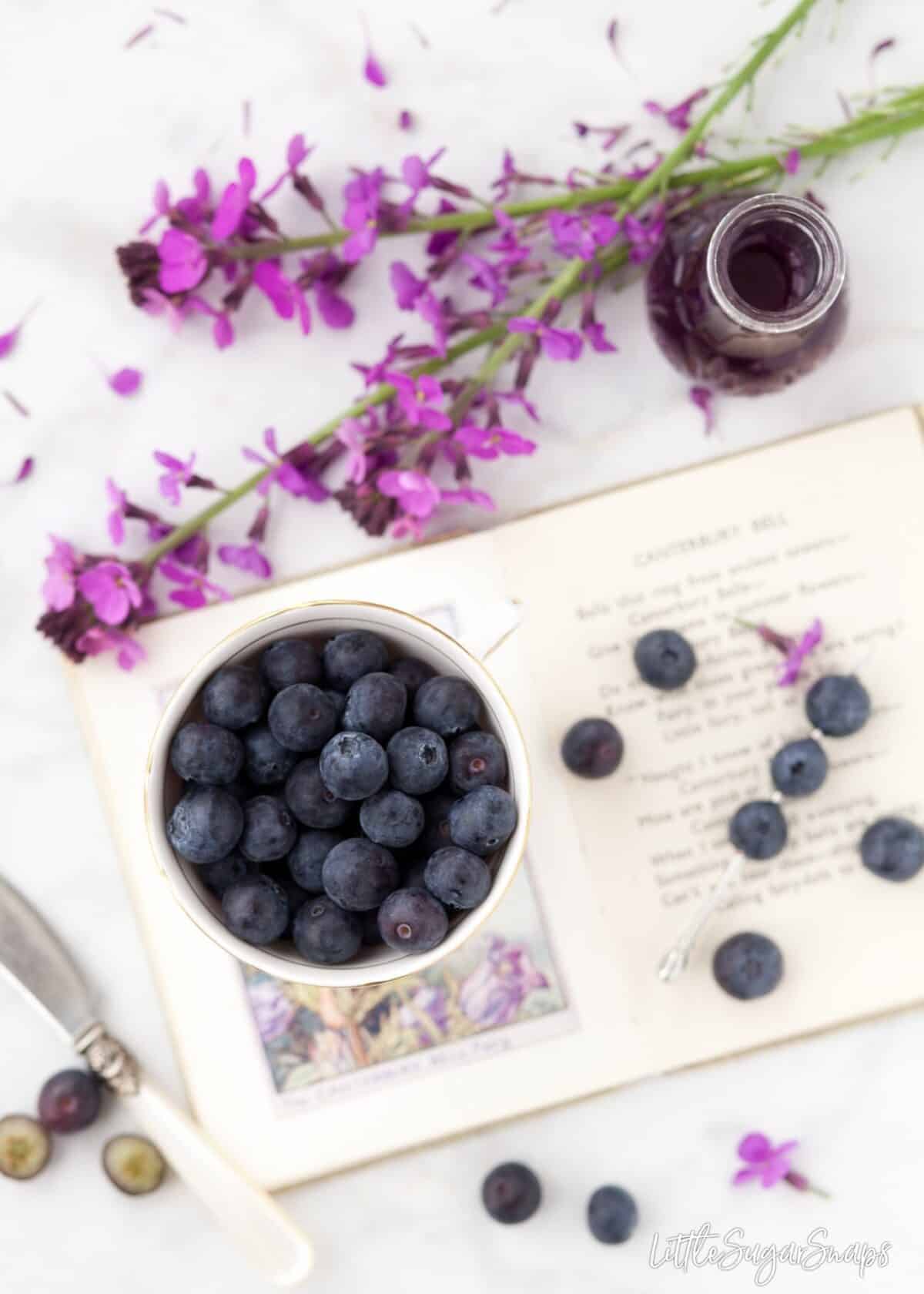 A bowl of blueberries with purple flowers