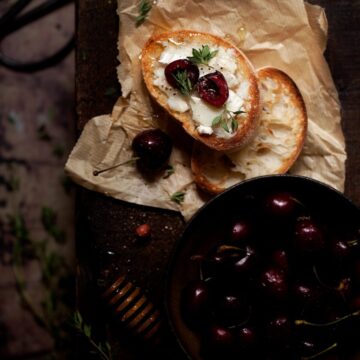 Cherry and Goats Cheese Crostini with honey drizzle on a bench