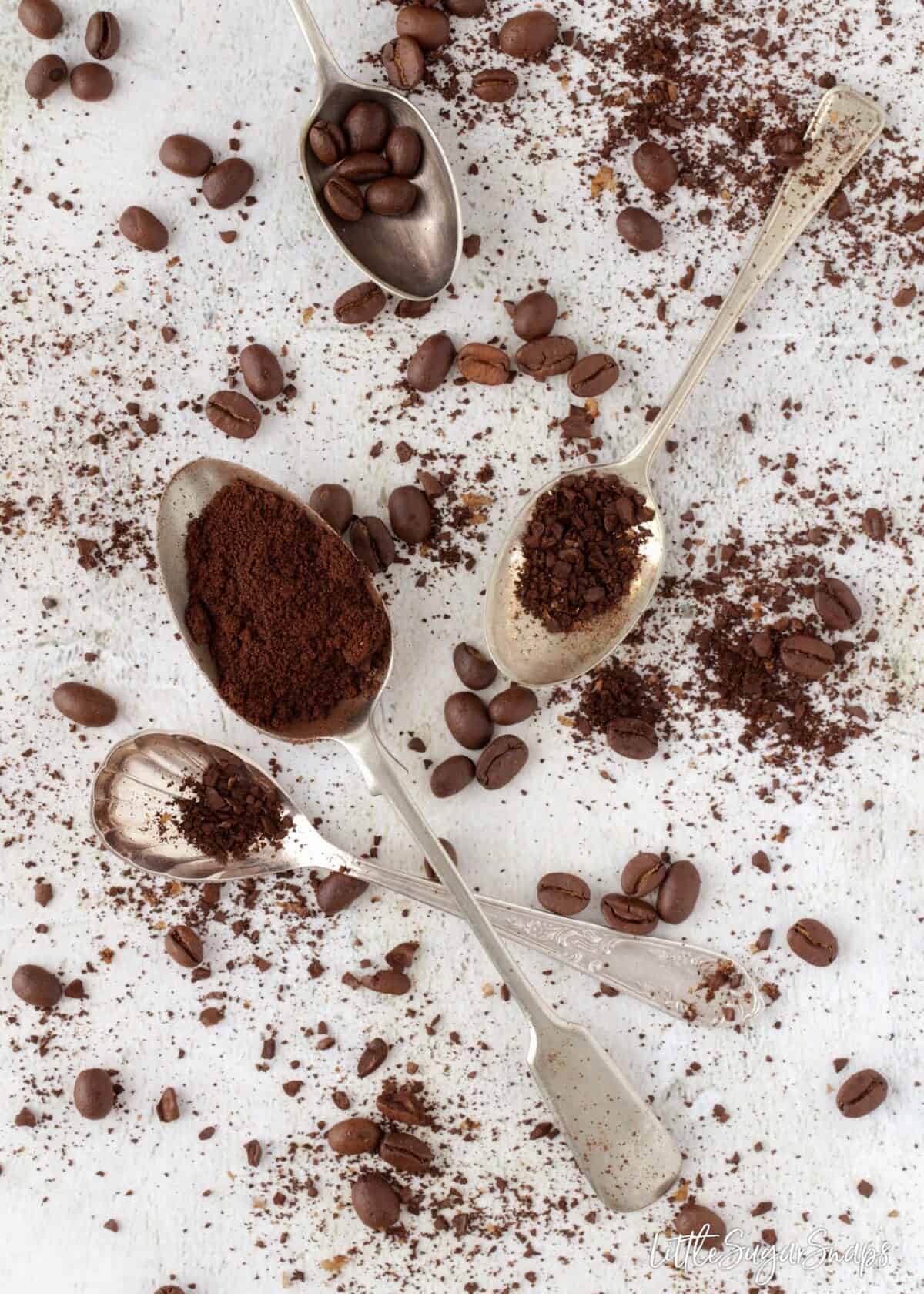 Coffee beans and ground coffee on old spoons.