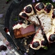 Part sliced blackberry cheesecake with one slice on it's side to reveal it's purple colour