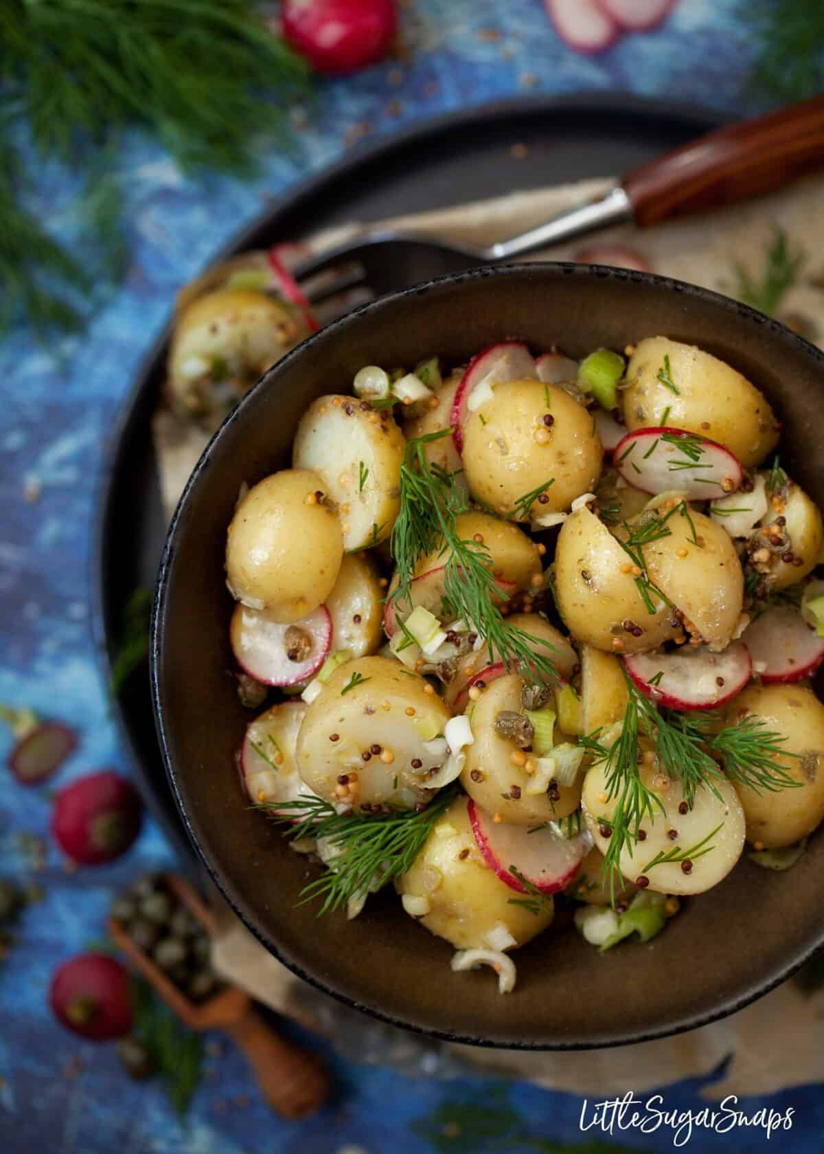 A bowl of potato salad with mustard vinaigrette, radish and dill.