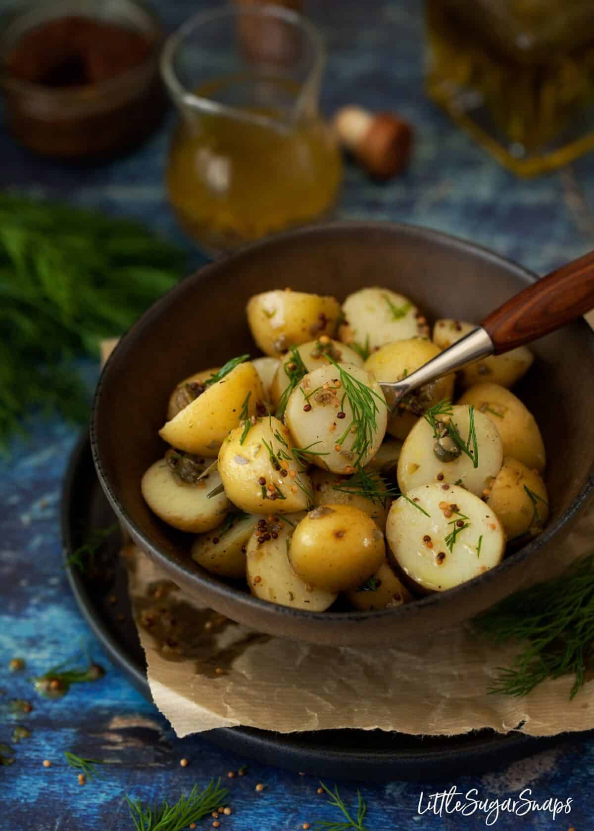 A bowl of potato salad with mustard vinaigrette, capers and dill