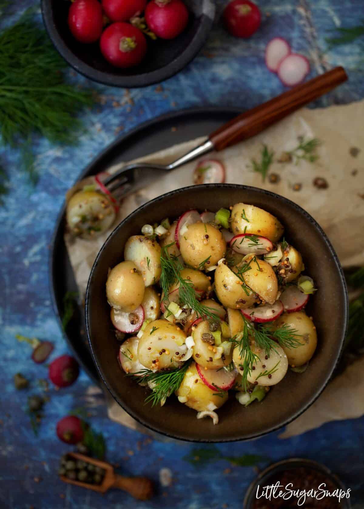 Overhead view of Potato salad with mustard vinaigrette, dill, radish and spring onion