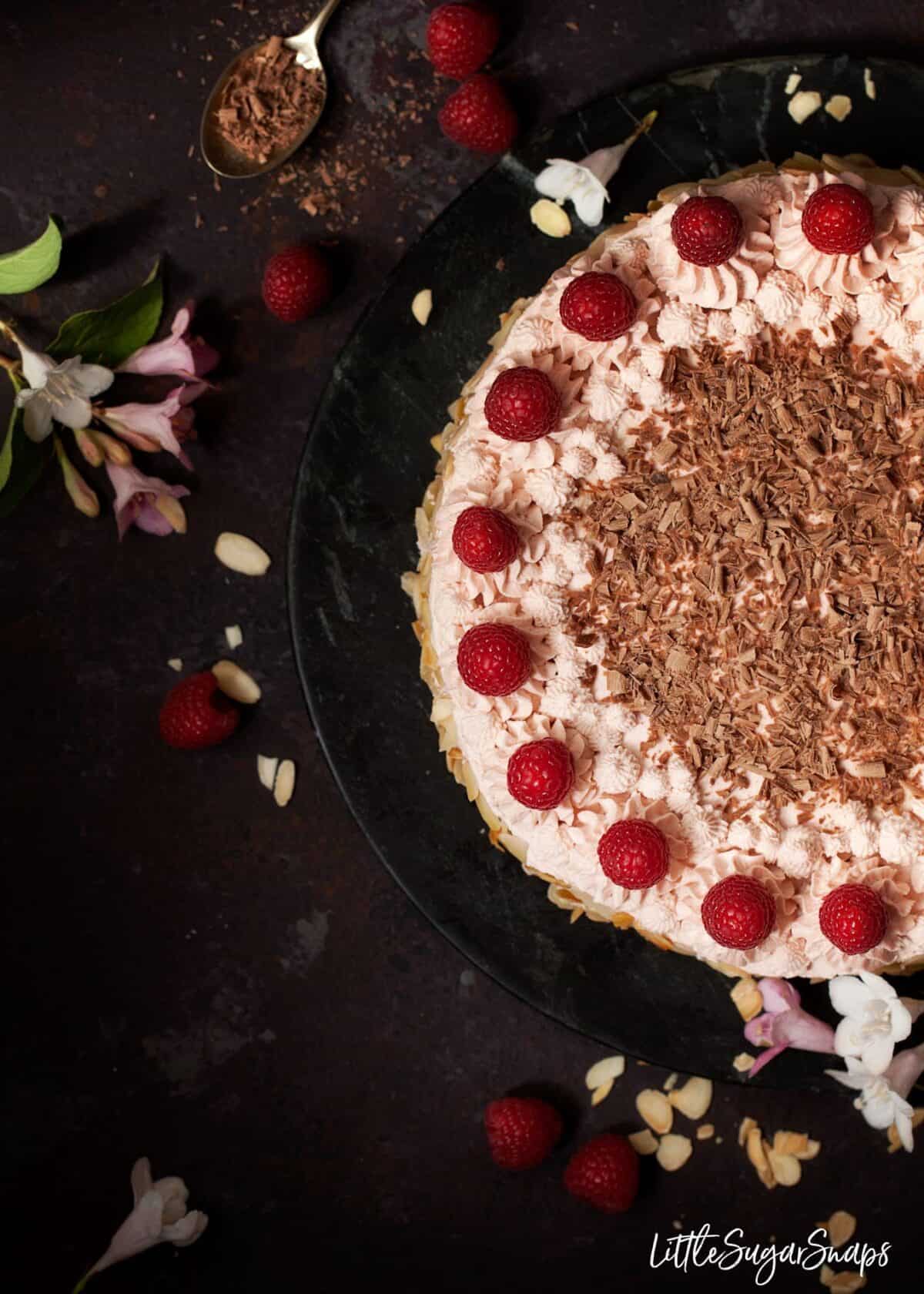 Topview of a raspberry gateau with piping cream, fresh raspberries and chocolate.