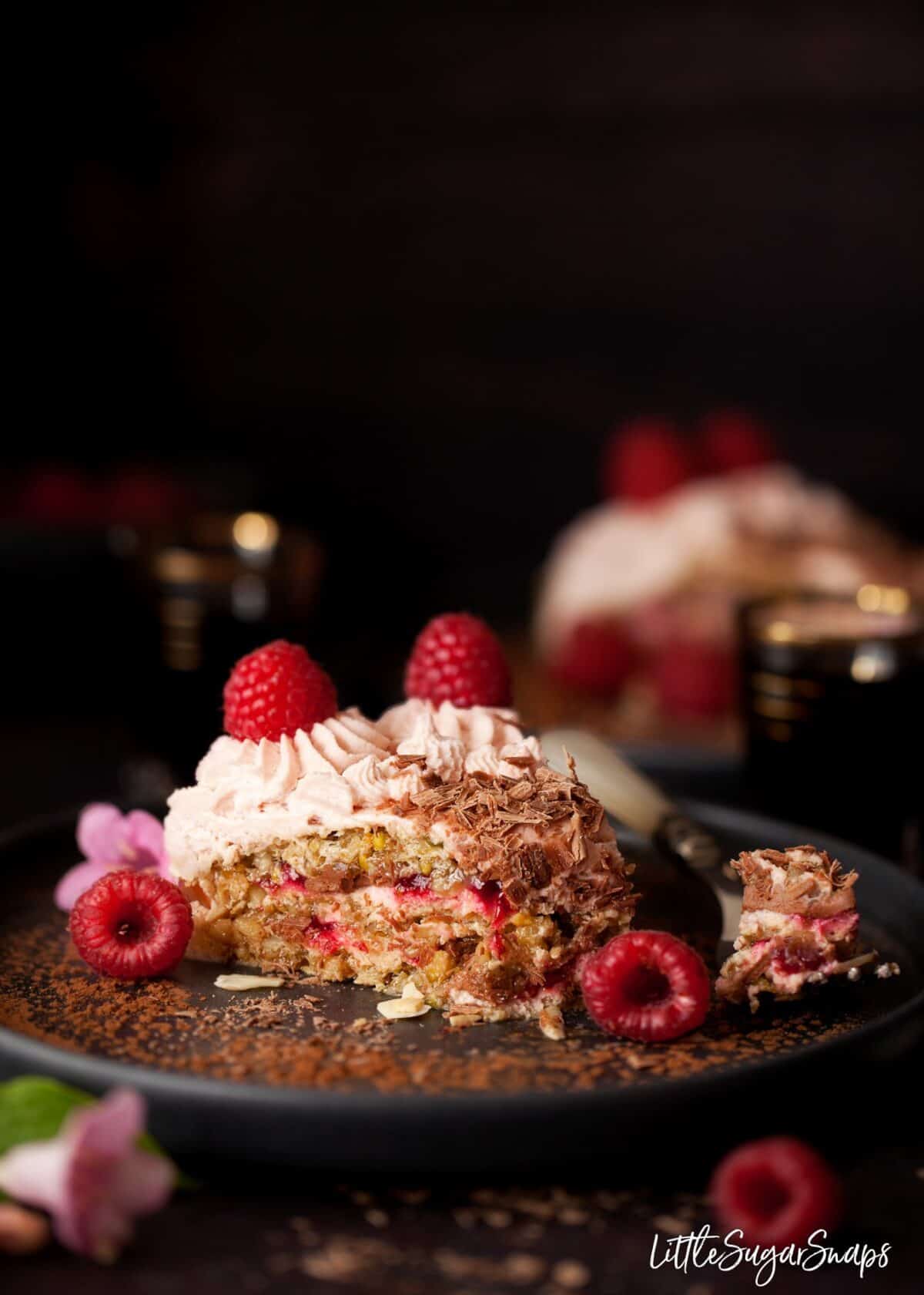 A slice of chocolate raspberry dacquoise cake on a black plate 