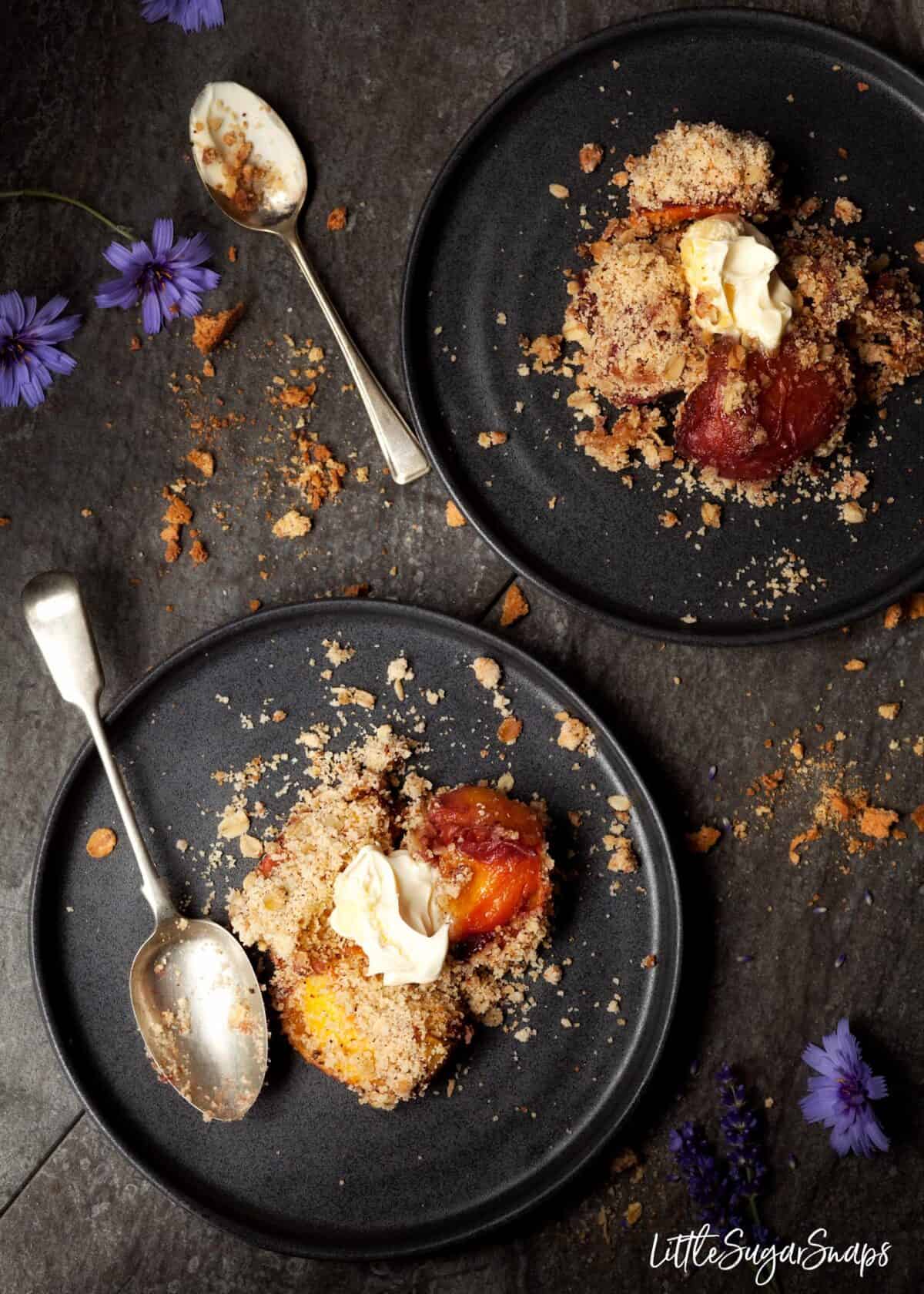 Two plates of peach crumble with clotted cream