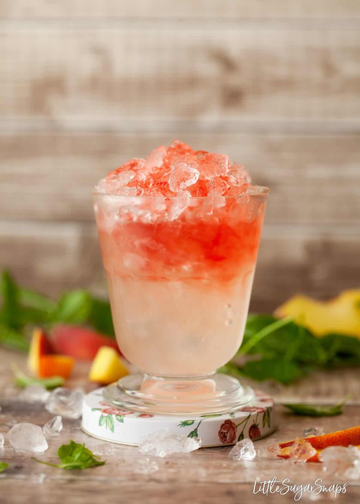 creme de framboise poured over a raspberry peach bramble cocktail