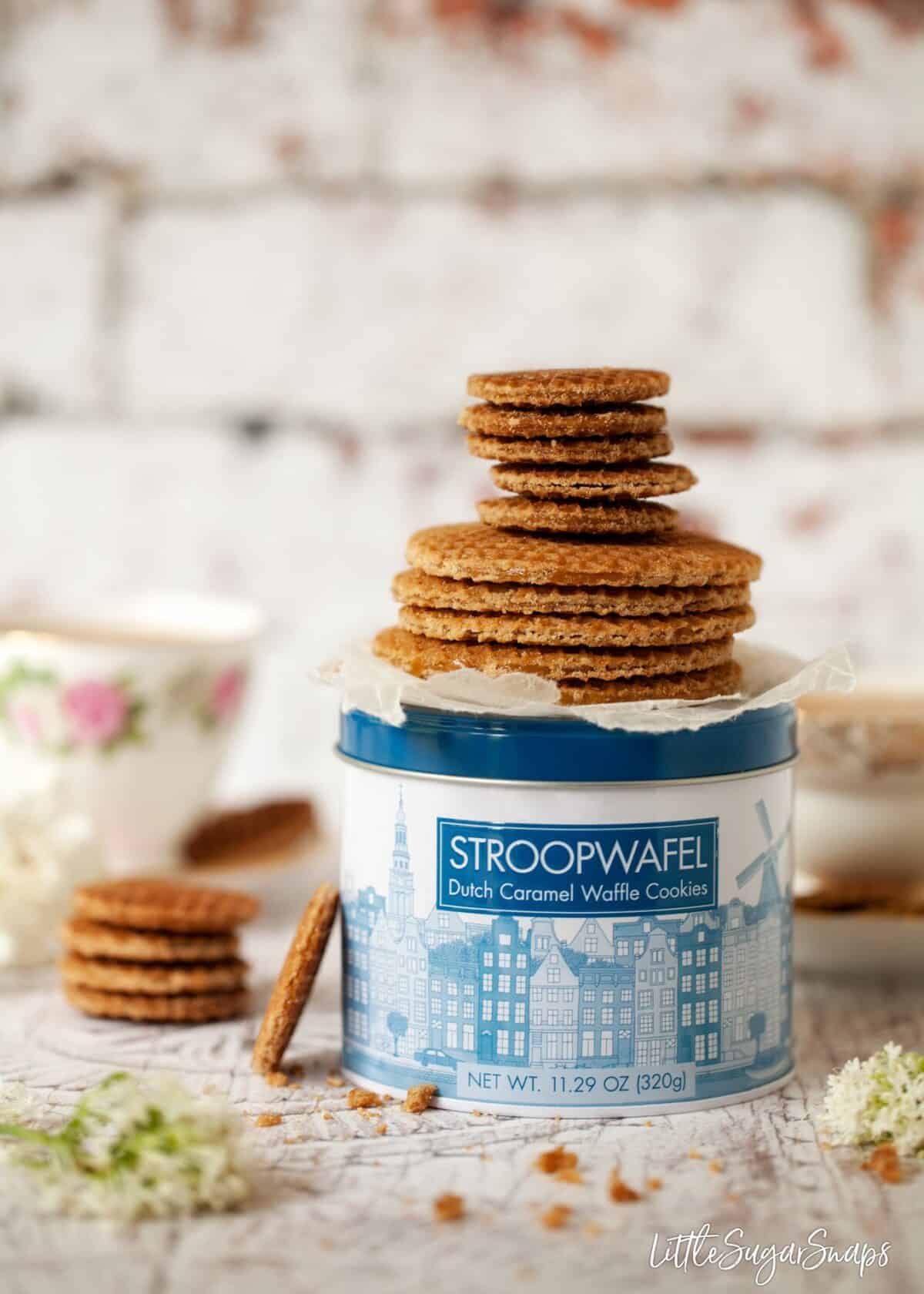 A stack of full size and mini caramel waffle cookies on a cookie tin