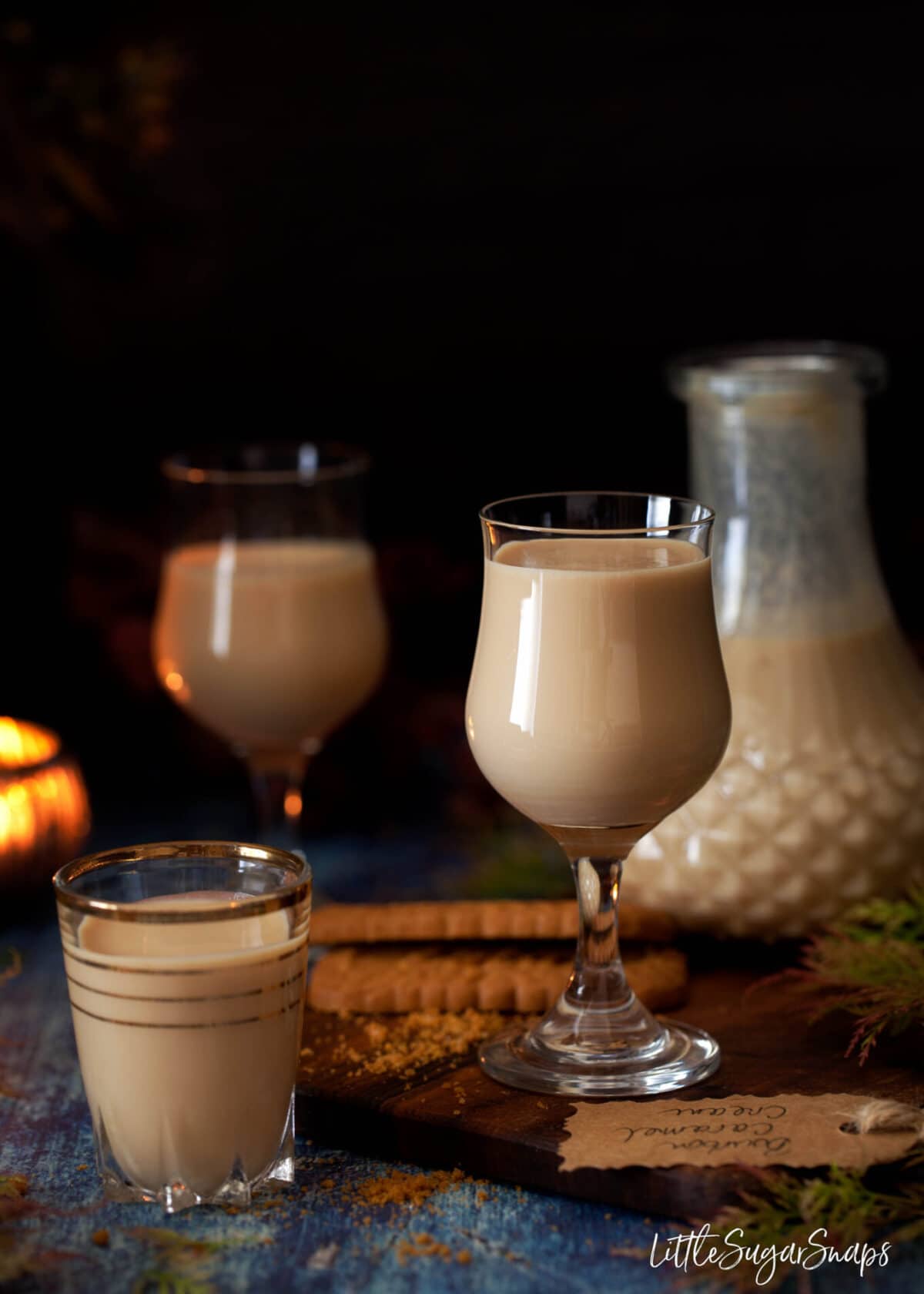 Glasses of creamy bourbon caramel liqueur poured into stem glasses and shot glasses.