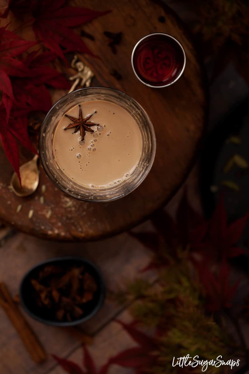 A glass of spiced tea garnished with star anise.