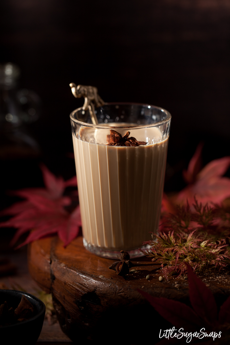 A glass of rum masala chia on a wooden stand with star anise garnish