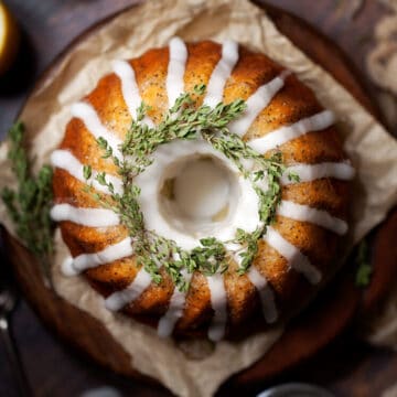 Fully decorated lemon bundt cake topped with water icing and fresh thyme. Top down view of the uncut cake