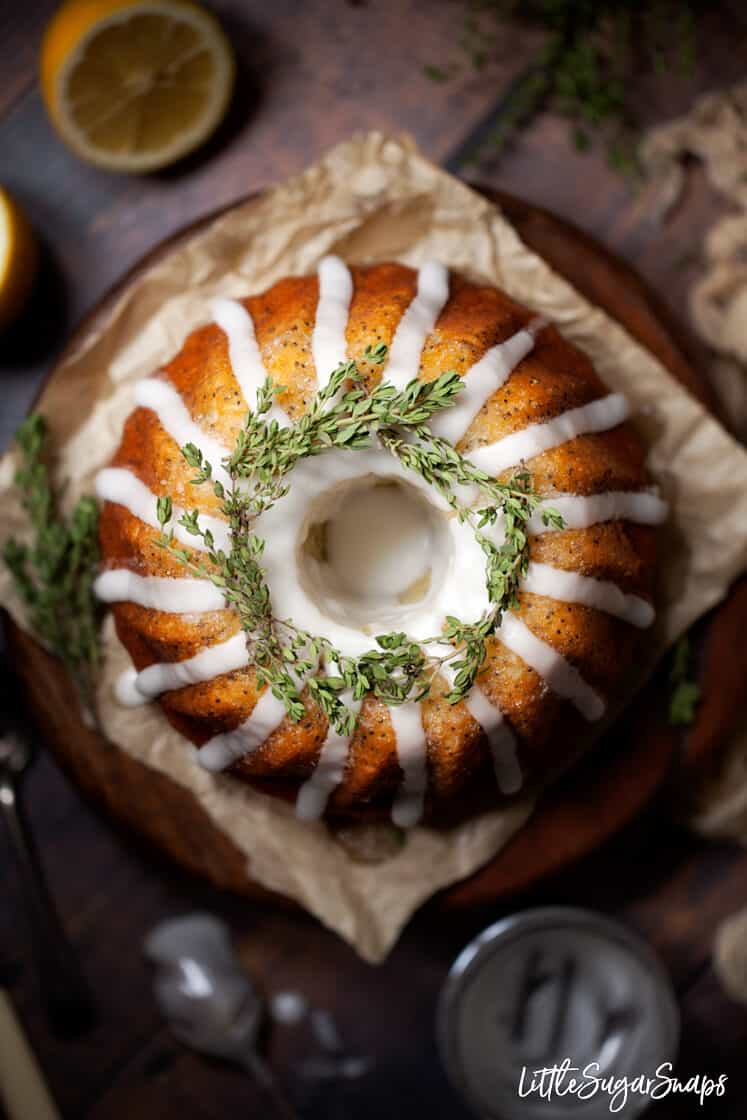 Overhead view of a lemon bundt cake with water icing and thyme garnish.