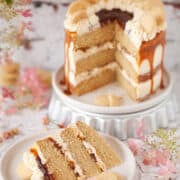 Millionaires Shortbread Cake with caramel and chocolate sauce with a slice cut out on a plate in front