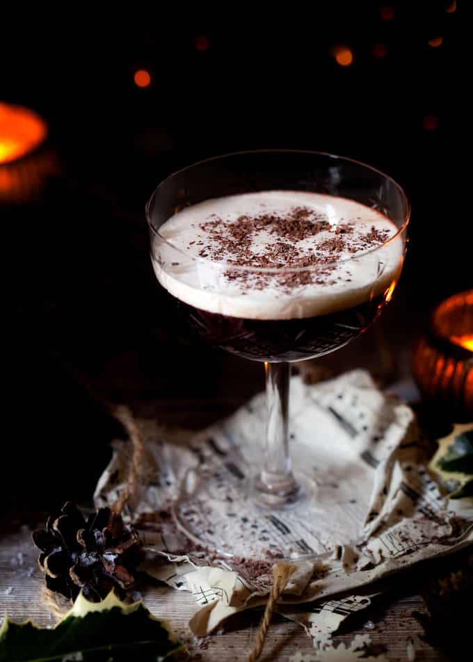 A blackberry cocktail with a cream float and chocolate flakes.