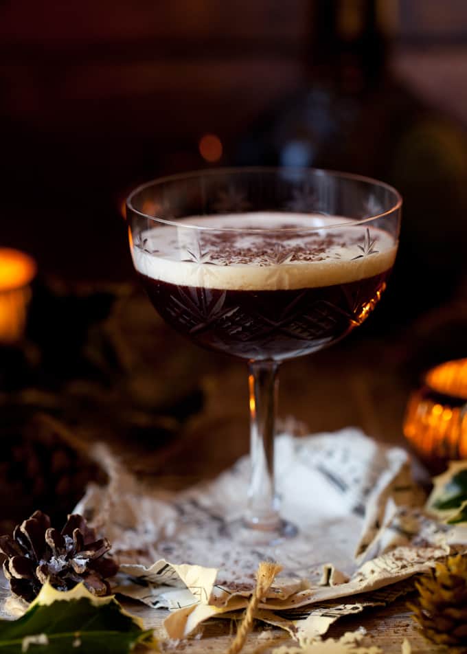 A blackberry cocktail in a vintage glass with a cream top and grated chocolate garnish.