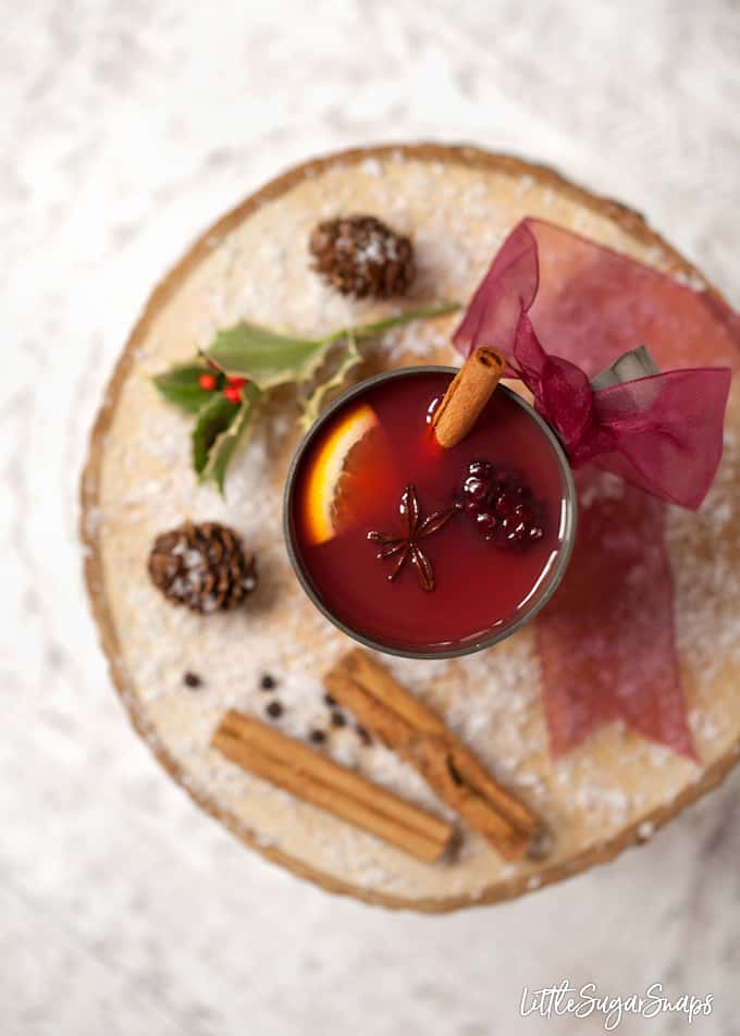 Vintage mug holding mulled apple juice with blackberries, star anise, cinnamon and orange.