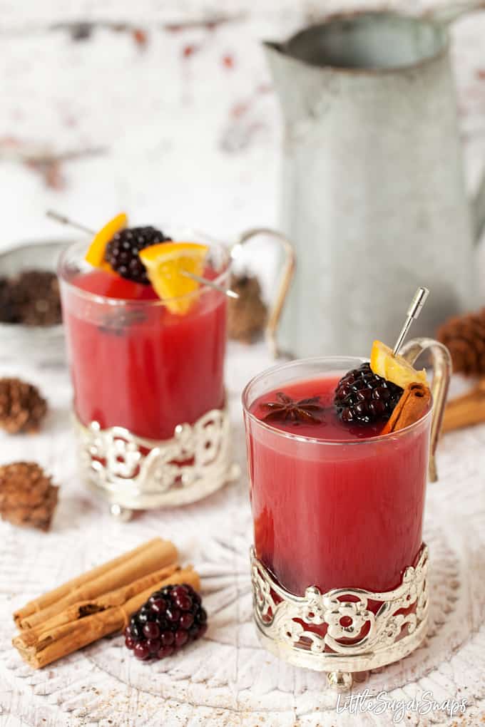 Hot mulled apple juice with blackberries in vintage glassware with cinnamon and star anise garnish