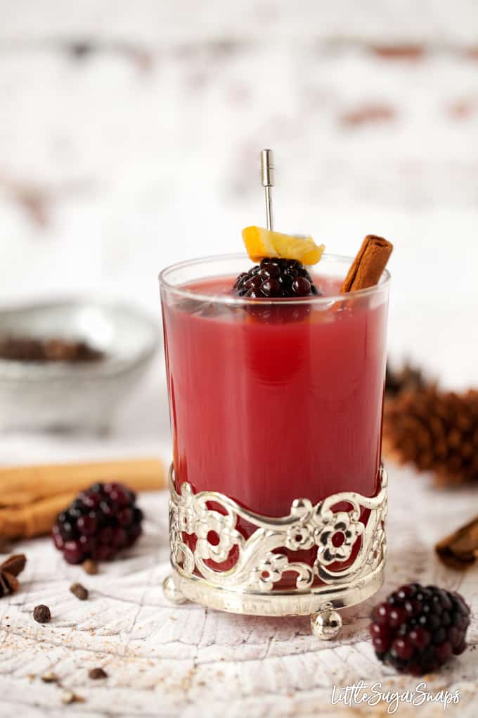 Hot mulled apple juice in vintage glassware with cinnamon, star anise and blackberry garnish