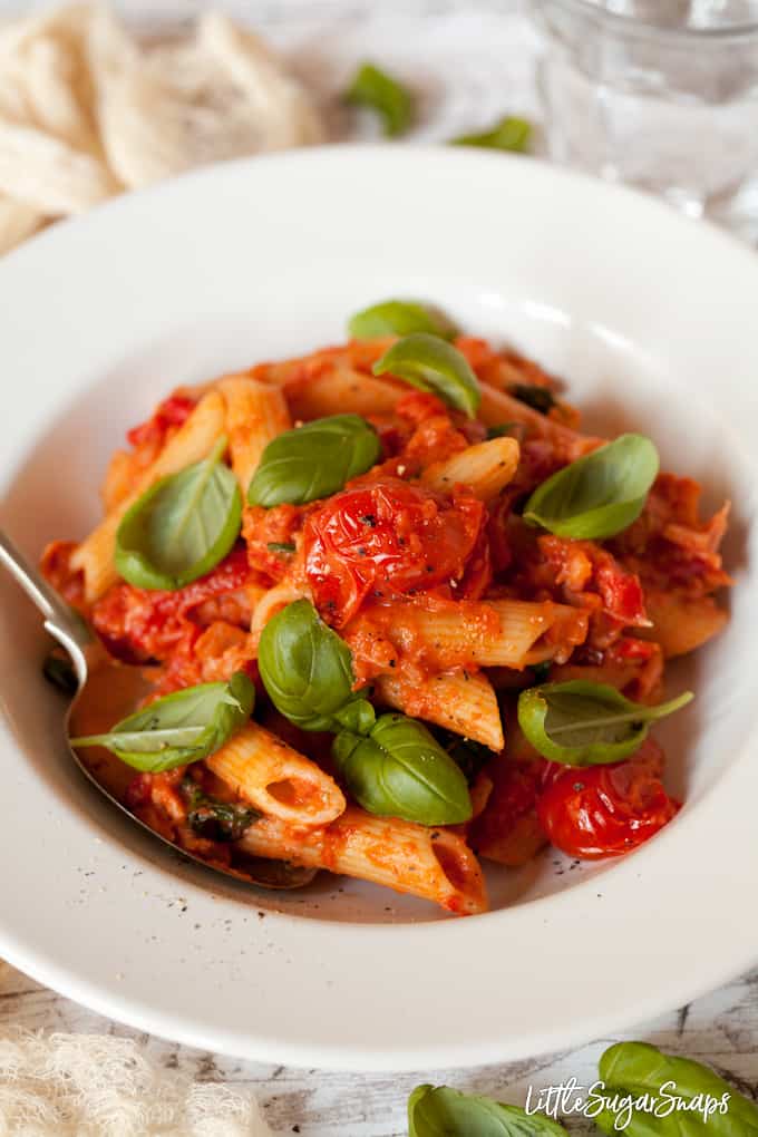 A white bowl filled with penne in tomato vodka sauce