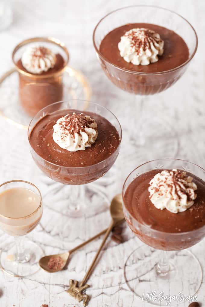 Assorted glasses of boozy chocolate mousse topped withe whipped cream.