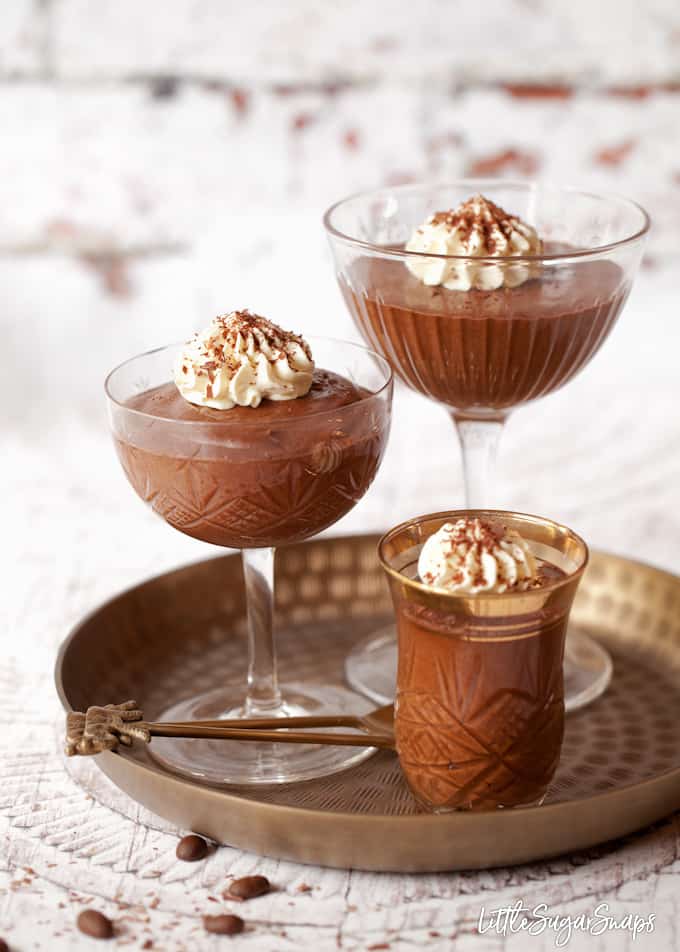 Assortment of glassed filled with boozy chocolate mousse on a metal serving tray.
