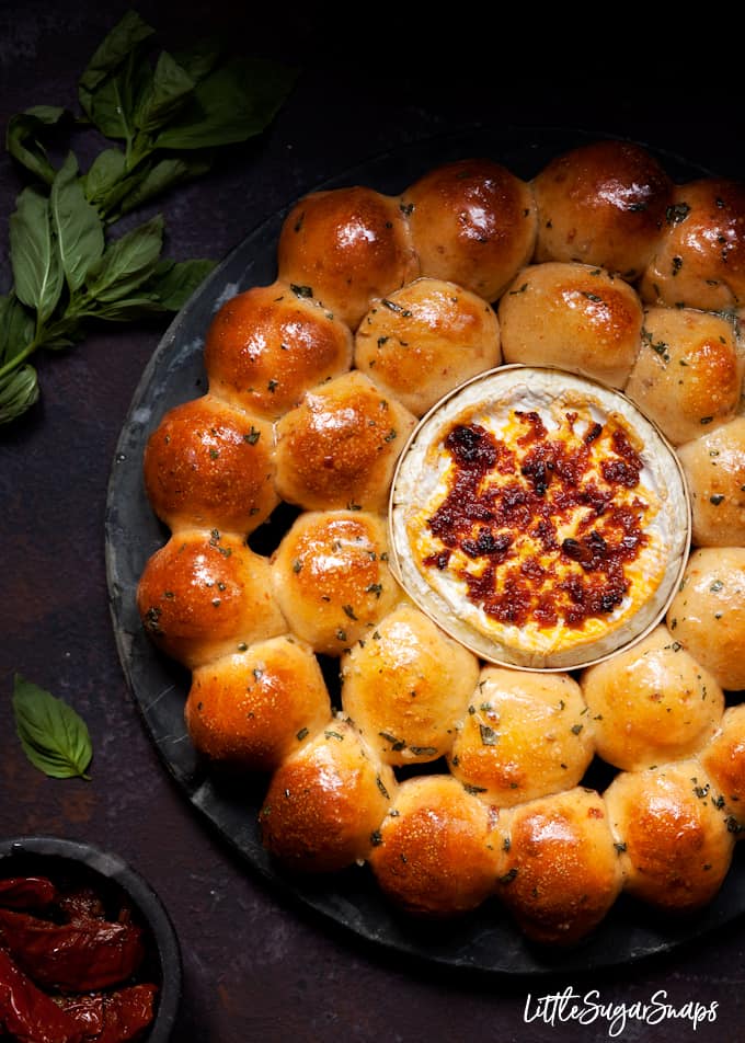 Freshly baked garlic butter dough balls with baked camembert and red pesto

