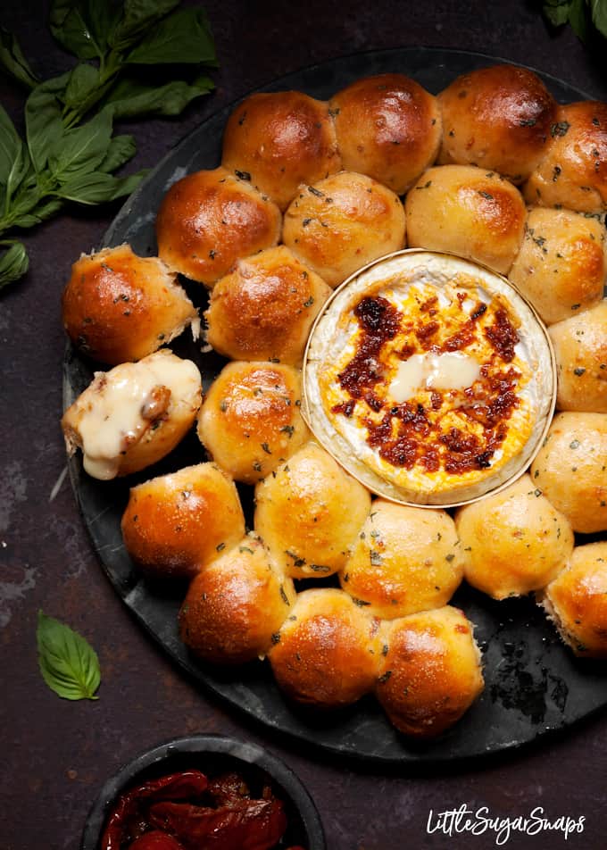 Dough Ball and Baked cheese platter with a piece of bread already dipped into the cheese. 