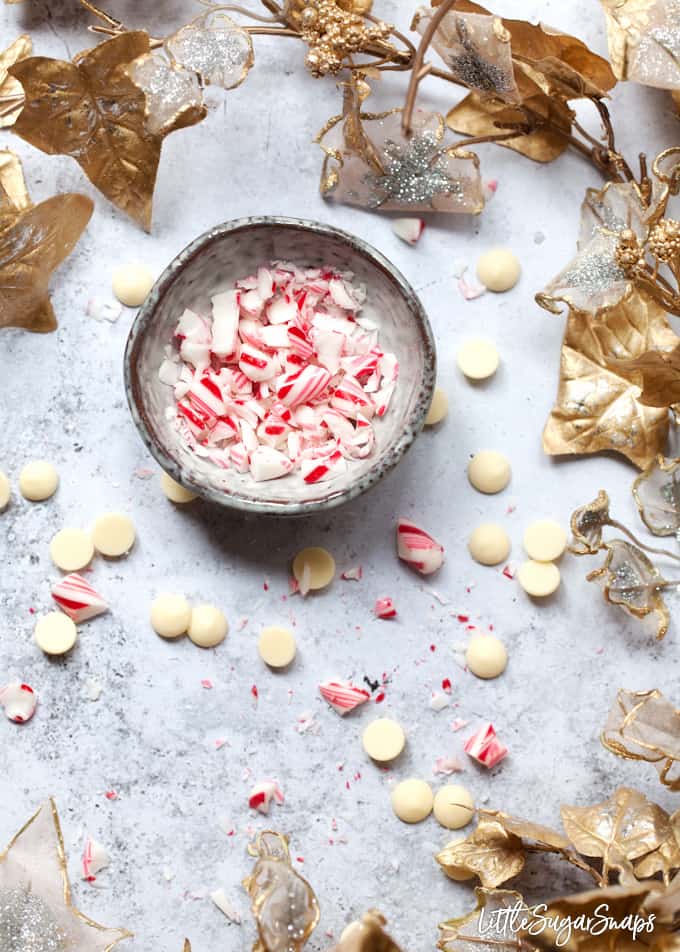 Crushed candy cane in a grey bowl with white chocolate chips around it. 