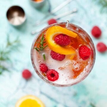 overhead view of a winter aperol spritz with sloe gin and rosemary