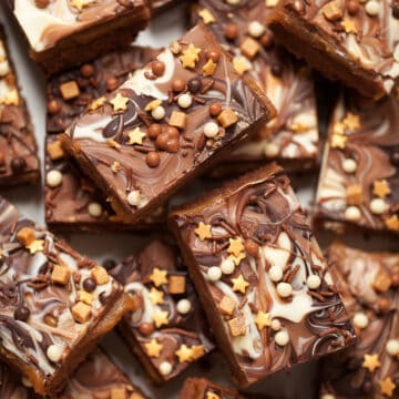 Chocolate Caramel Shortbread Bars topped with marbled chocolate and mixed srpinkles including fudge pieces, vermicilli strands, crunchy chocolate balls and gold stars