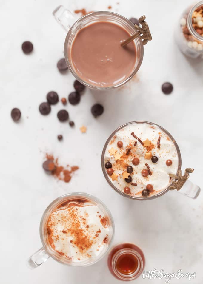 Overhead view of glasses of bourbon hot chocolate. Two are topped with cream and sprinkles.