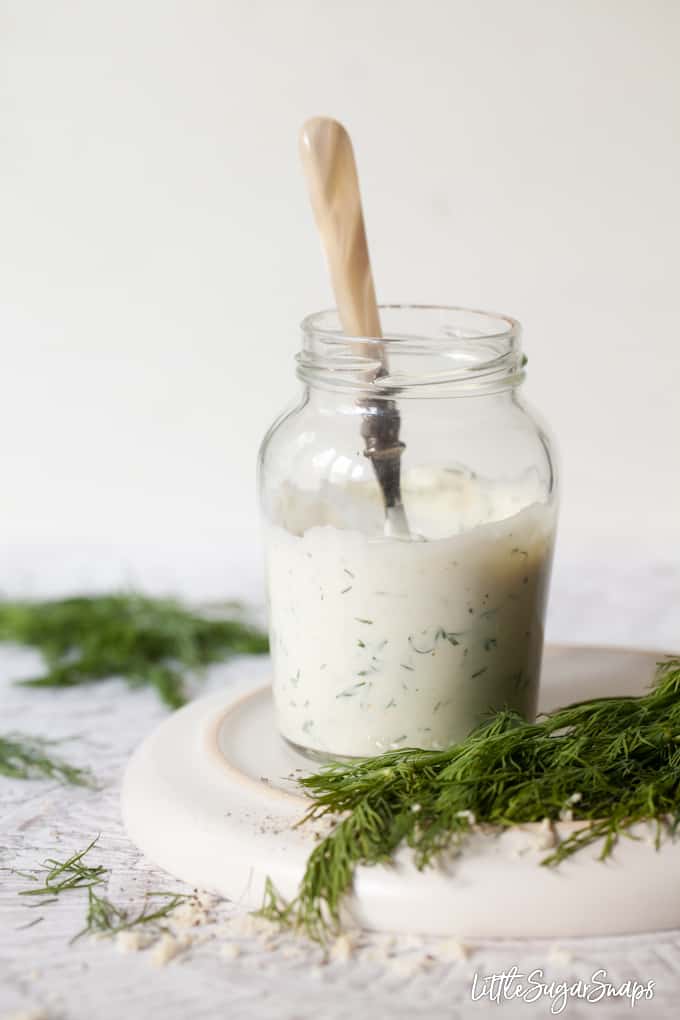 Creamy salad dressing in a jar with fresh dill and grated horseradish
