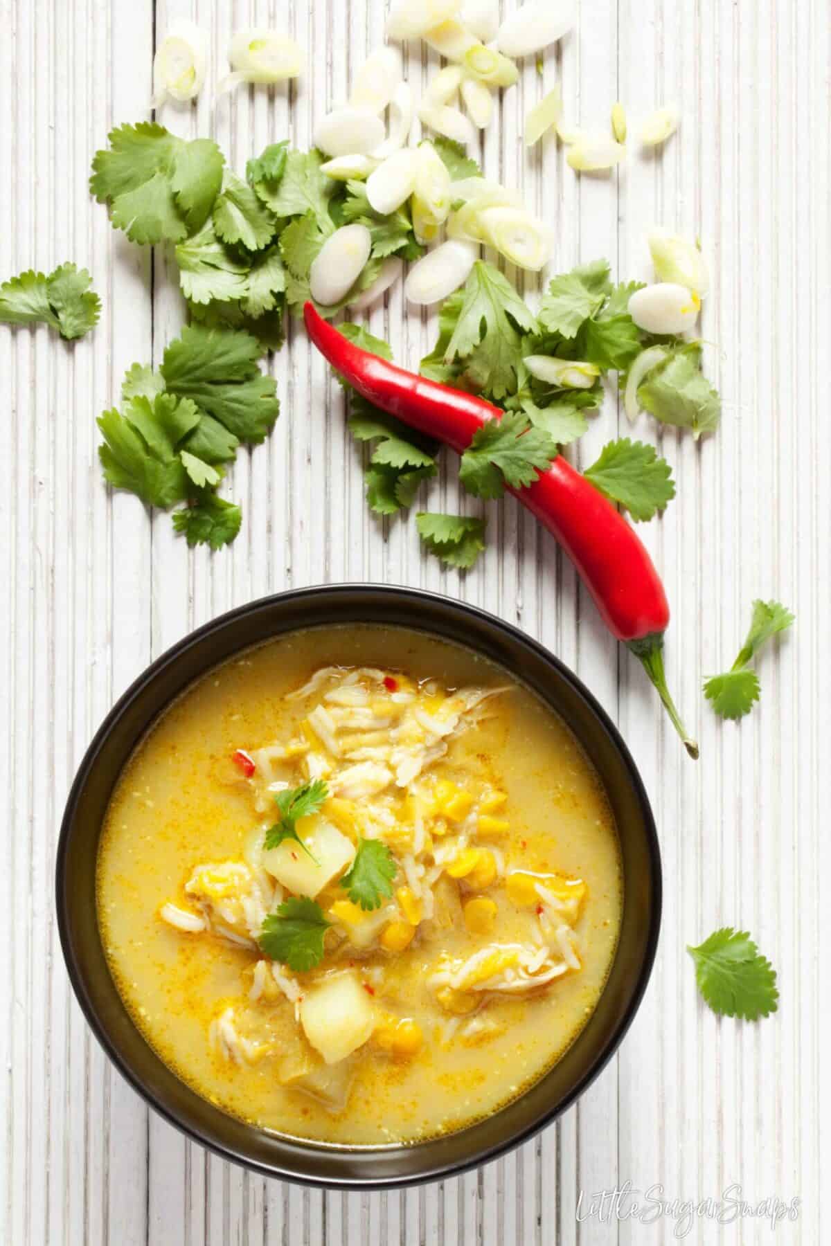 A bowl of split pea, chicken & rice soup with coriander and chilli alongside.