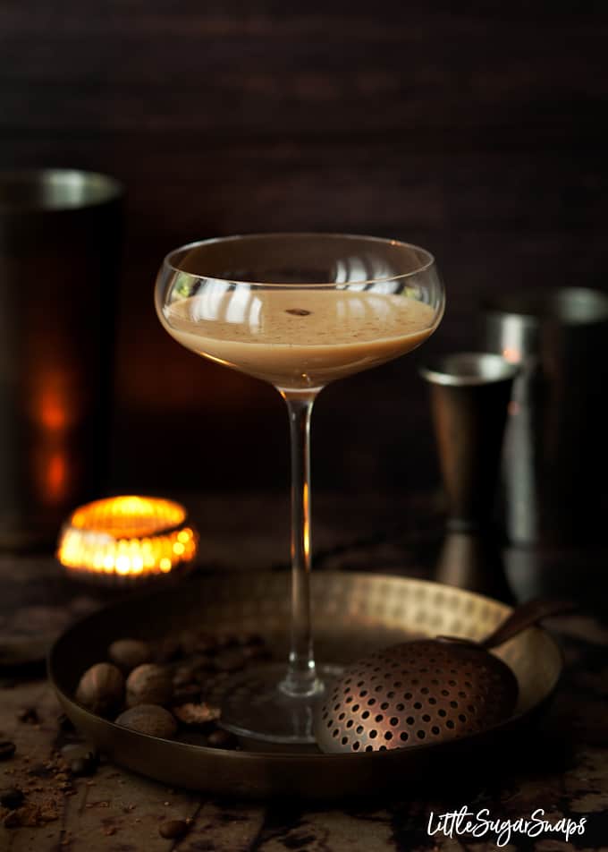 A Coffee Brandy Alexander cocktail in a tall glass, garnished with grated nutmeg and a coffee bean.