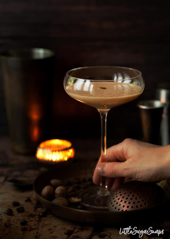 Person taking a cocktail glass filled with a creamy coffee cocktail.