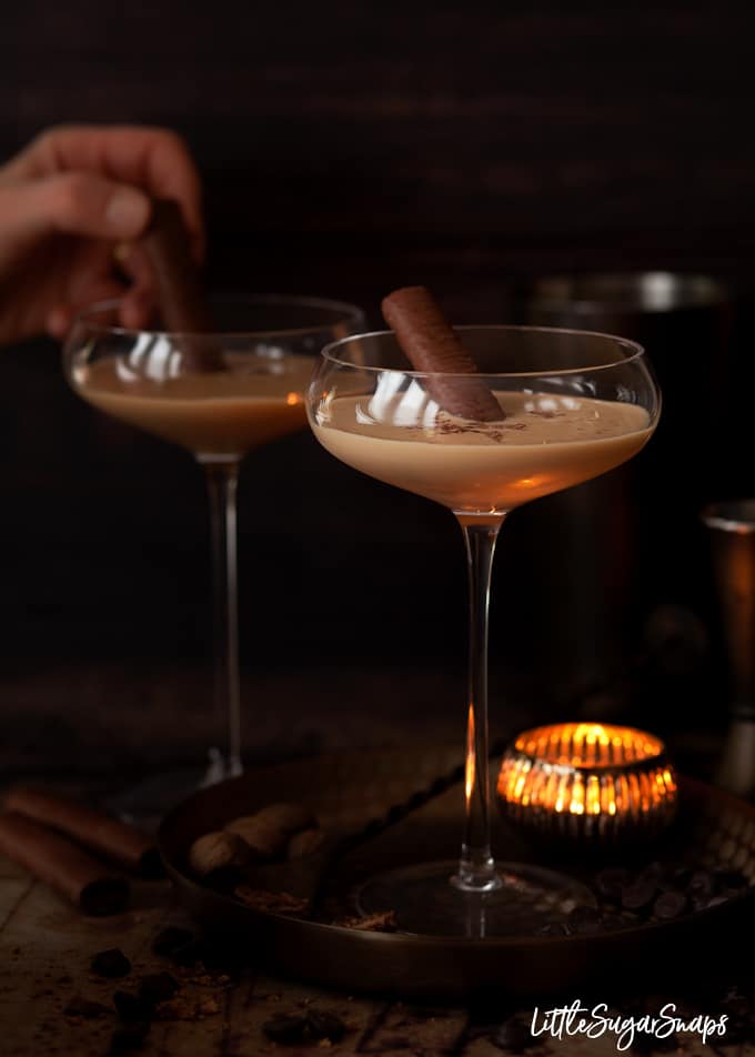 Person adding chocolate wafers to creamy brandy alexander cocktails.